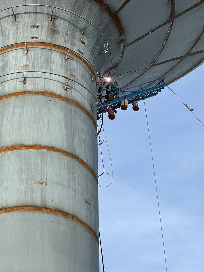Boilermaker welding overhead beneath an elevated water tower